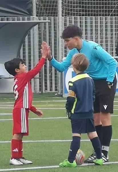 Árbitro saludando a jóvenes futbolistas antes de un partido